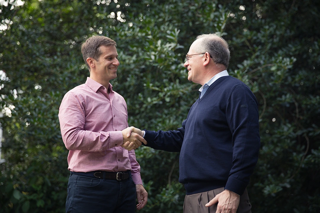 J. Mark Baiada shaking hands outdoors in a candid editorial-style photo