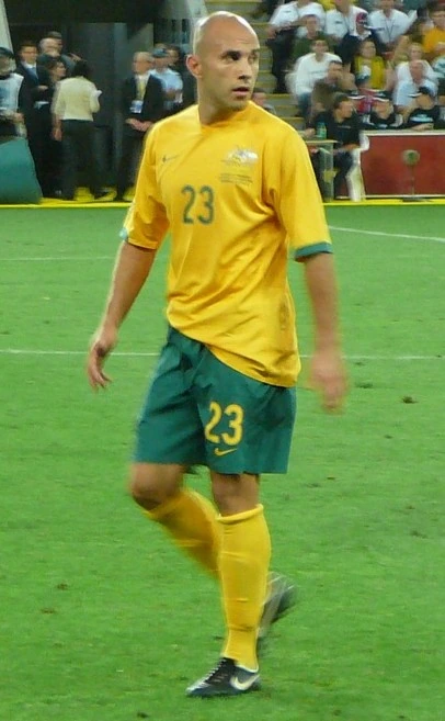 Mark Bresciano in a yellow Australia soccer kit on the field