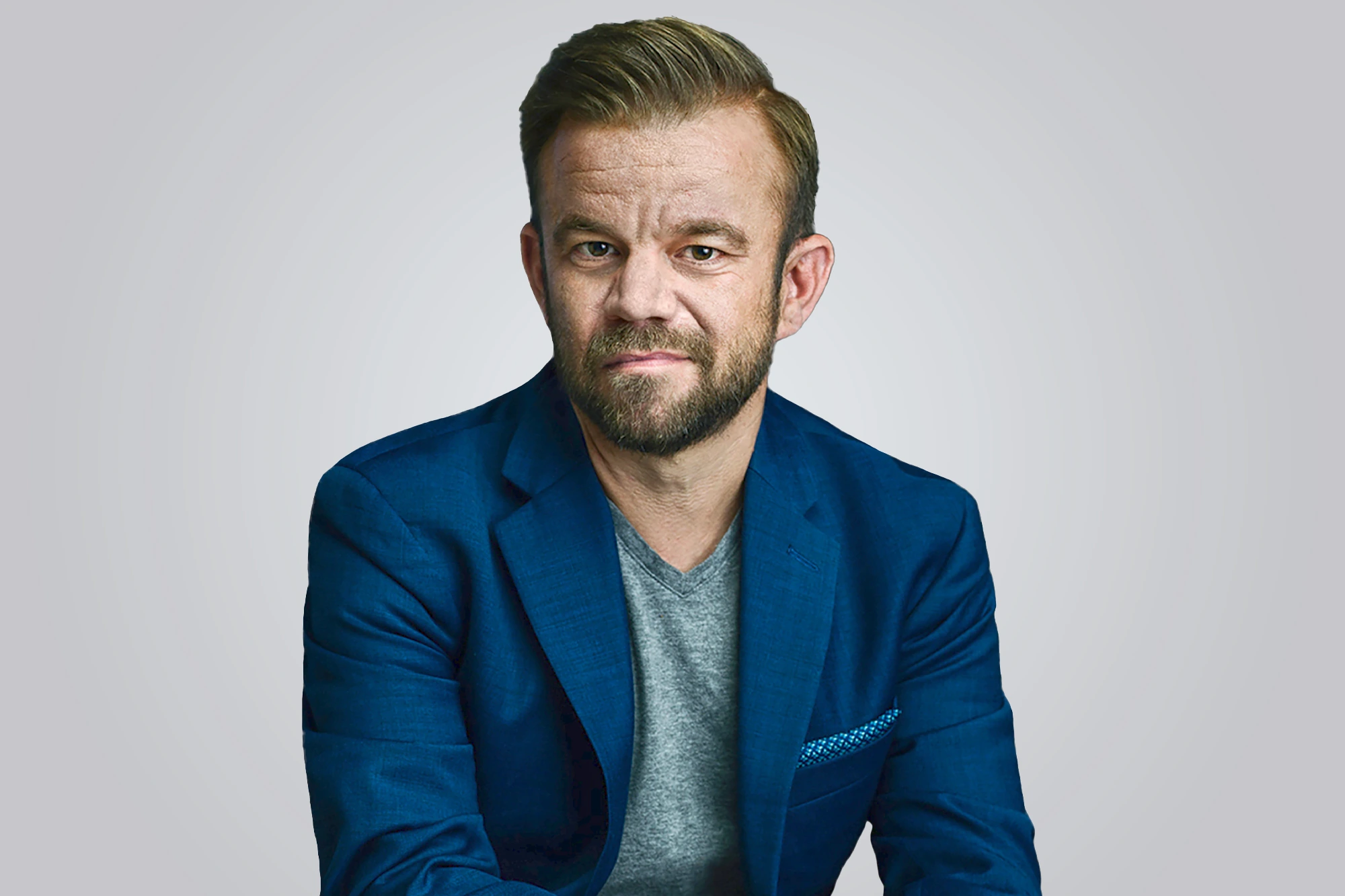 Portrait photo of Mark Black in a blue blazer against a light gray background