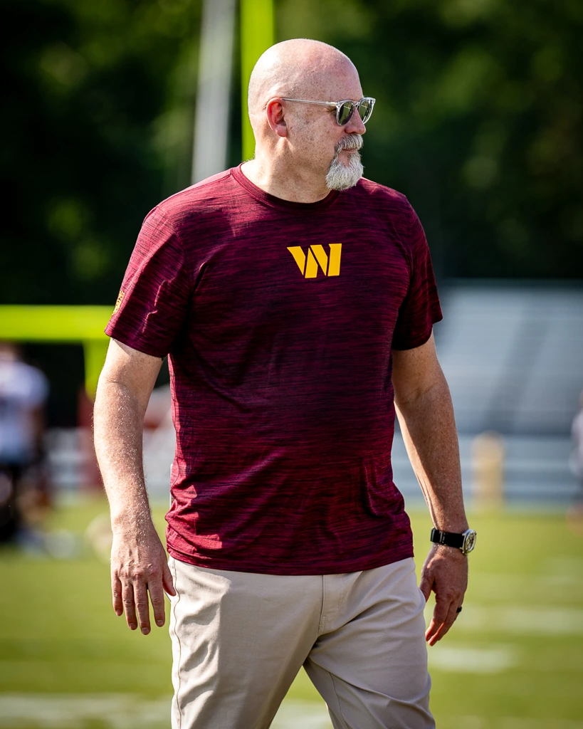 Mark Clouse standing on a football field in a Washington Commanders shirt, photographed outdoors in a candid editorial-s